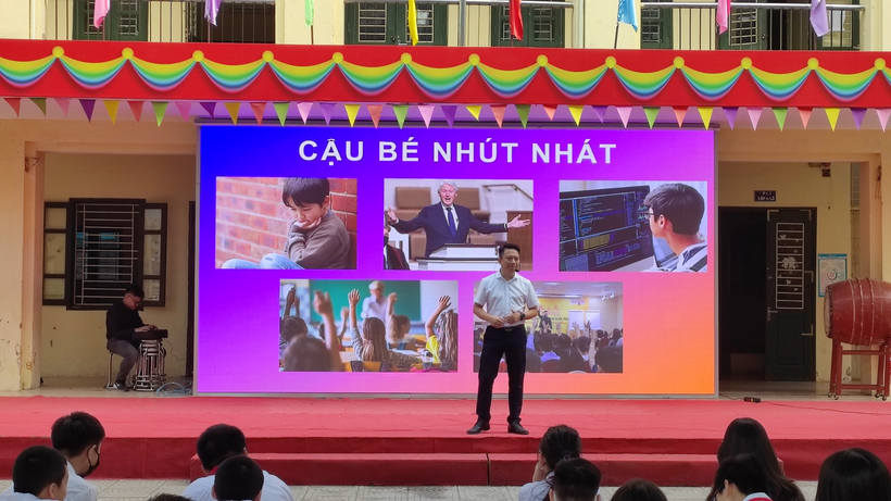 A person standing on a stage with a large screen behind him

Description automatically generated with medium confidence