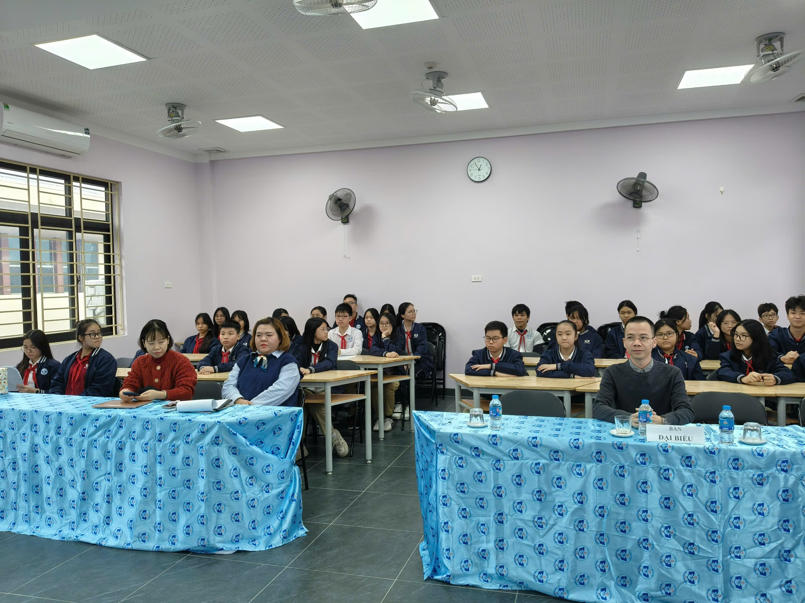 A group of people sitting at tables in a classroom

Description automatically generated
