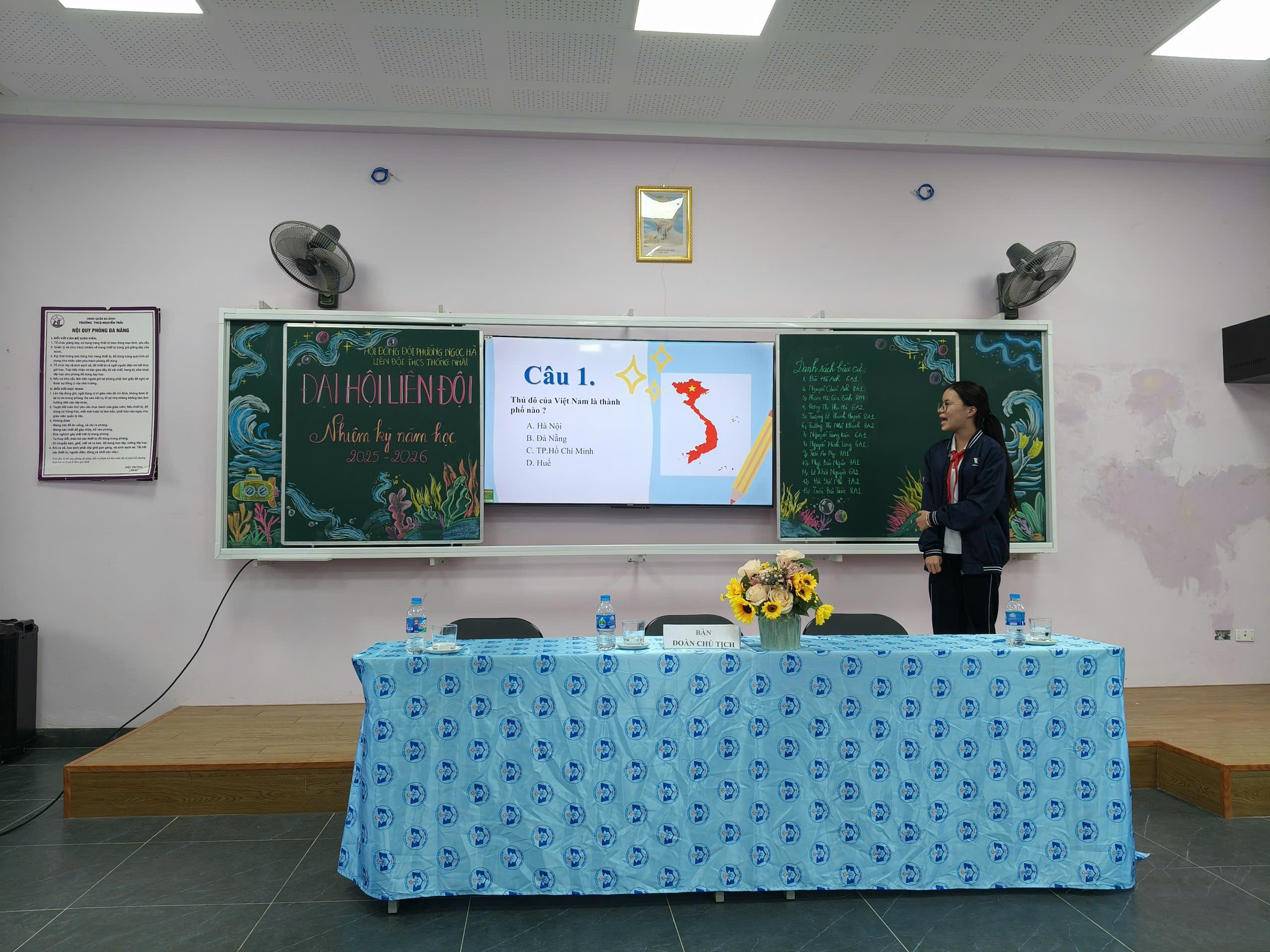 A person standing in front of a table with a blue tablecloth

Description automatically generated