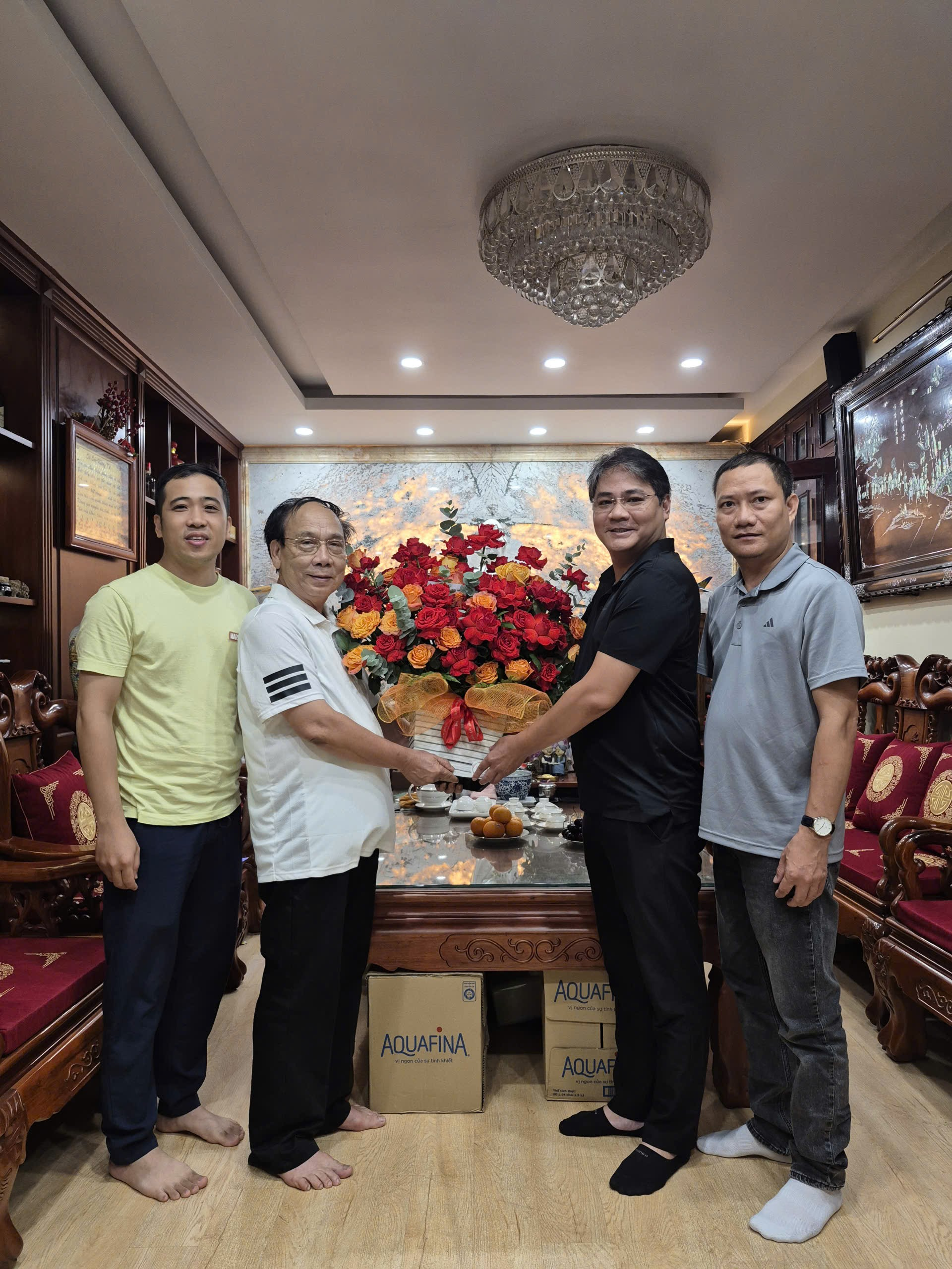 A group of men standing in a room with a table with flowers

Description automatically generated