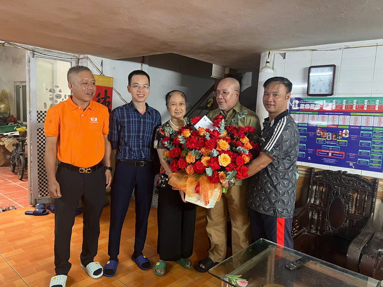 A group of people standing in a room with a basket of flowers

Description automatically generated